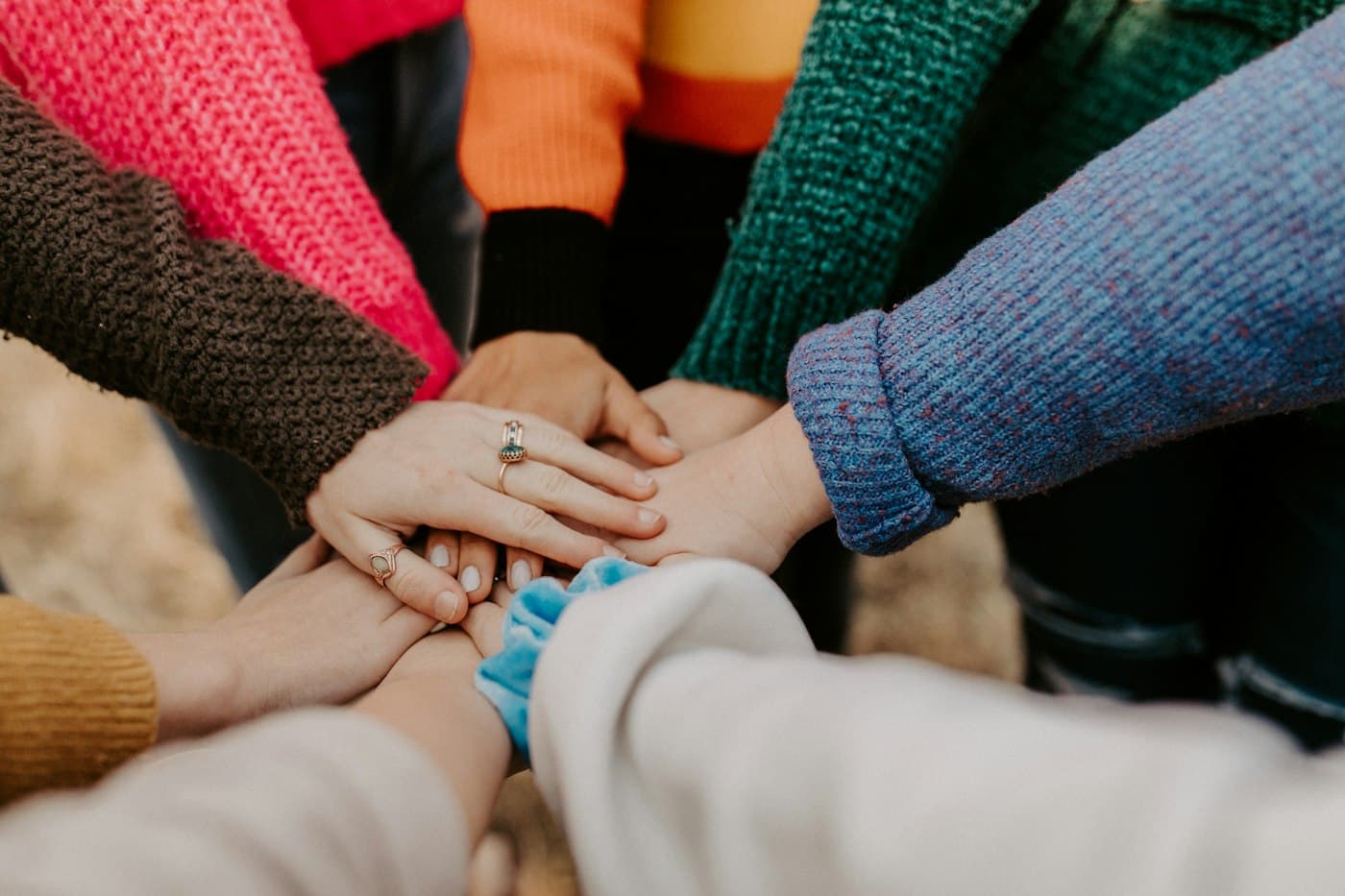 Manos de varias personas unidas en el centro, en señal de equipo