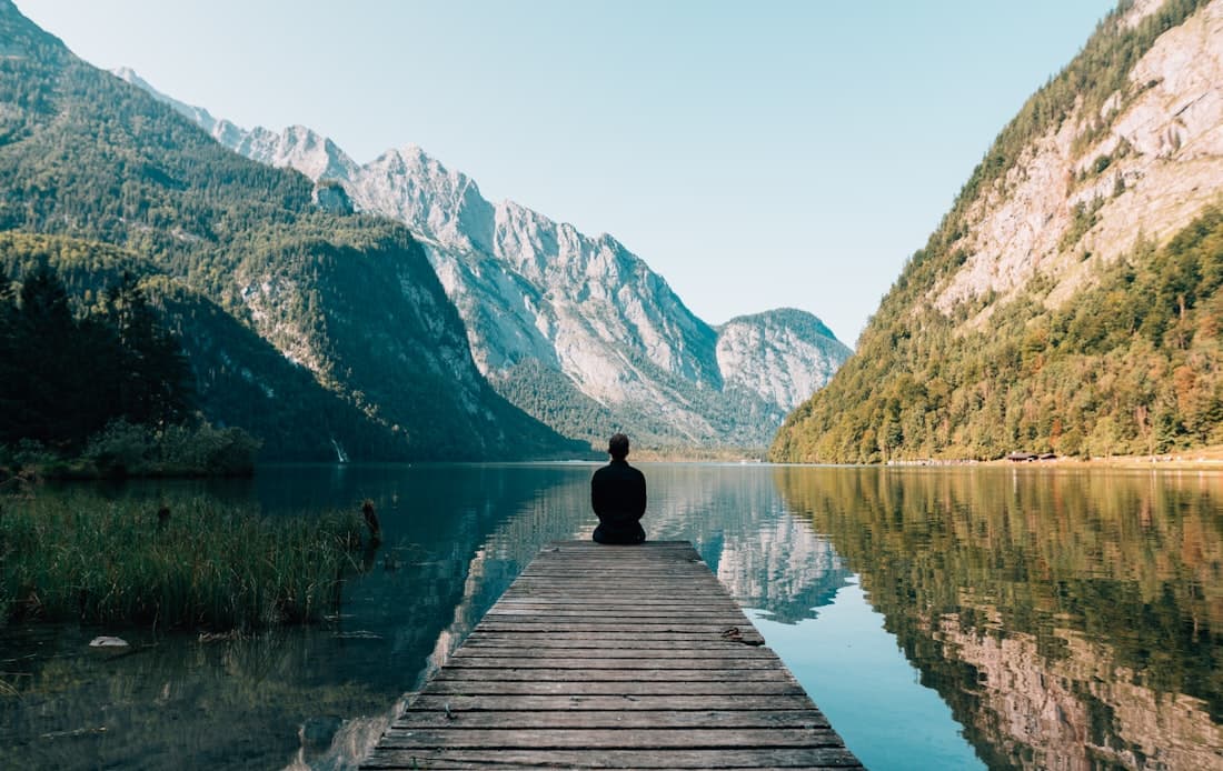 Persona en calma frente a un lago de montaña